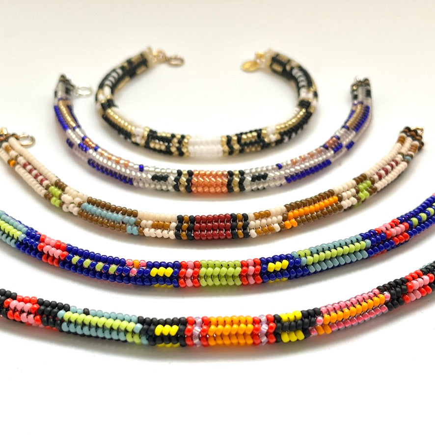 Five beaded bracelets arranged in a fan shape on a plain white background, each featuring different colorful bead patterns.